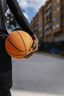 Junger Mann hält Basketball auf Basketballplatz - EGAF00032