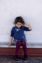 Little girl sitting on rooftop looking at cell phone - EGAF00041