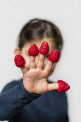 Girl's hand with raspberries on fingers - MGIF00923