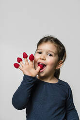 Portrait of girl with raspberries on fingers - MGIF00924