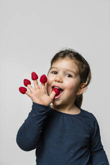 Porträt eines Mädchens mit Himbeeren an den Fingern - MGIF00924