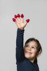 Porträt eines glücklichen Mädchens mit Himbeeren an den Fingern - MGIF00926