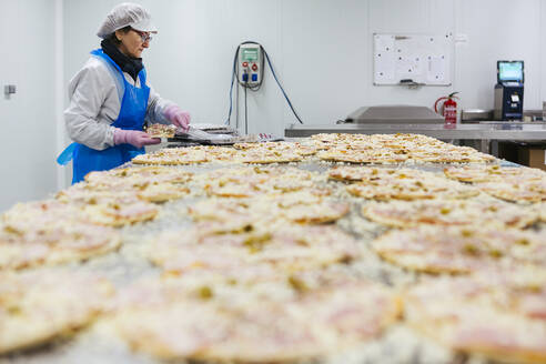 Frau bei der Zubereitung von Pizzen in einer Pizzafirma - XLGF00134