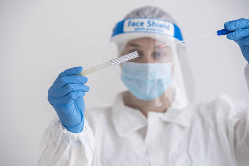 Woman in protective wear putting a swab into a tube - SNF00047