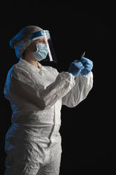 Woman in protective wear holding syringe - SNF00060