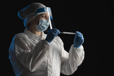 Woman in protective wear putting a swab into a tube - SNF00063