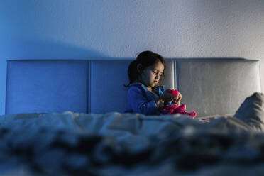 Kleines Mädchen sitzt auf dem Bett und spielt mit ihrem Spielzeug - EGAF00044