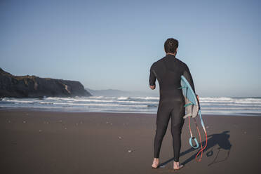 Rückansicht eines behinderten Surfers mit Surfbrett am Strand - SNF00080