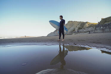 Behinderter Surfer mit Surfbrett am Strand stehend - SNF00083