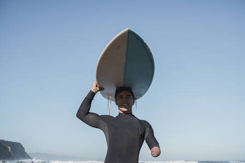 Behinderter Surfer trägt sein Surfbrett auf dem Kopf - SNF00085