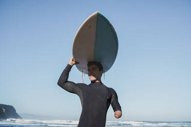 Behinderter Surfer trägt sein Surfbrett auf dem Kopf - SNF00086