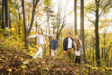 Lächelnde Eltern, die ihre Kinder beim Spielen im Herbst im Wald beobachten - WFF00394