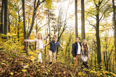 Boy and girl enjoying by parents in forest during autumn - WFF00395