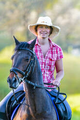 Porträt einer lächelnden jungen Frau auf einem Pferd - STSF02533