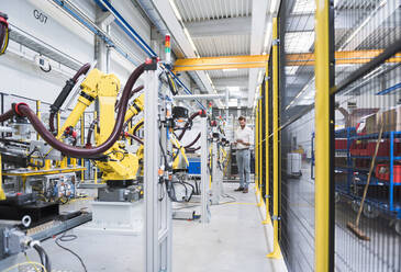 Selbstbewusster Ingenieur in voller Länge bei der Arbeit in einer automatisierten Roboterfabrik - DIGF10403