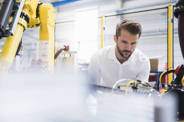 Engineer examining robotic arm in factory - DIGF10406