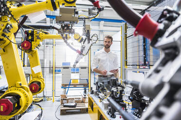 Selbstbewusster Robotikexperte bei der Betrachtung von Maschinen in einer Produktionsstätte - DIGF10412