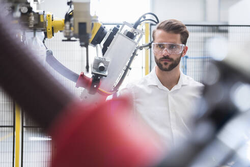 Selbstbewusster Experte betrachtet den Roboterarm in der automatisierten Fabrik - DIGF10418