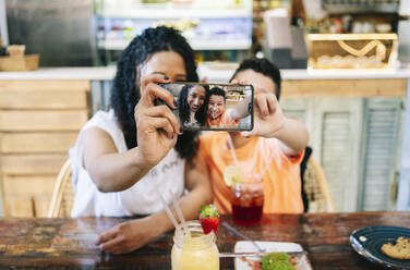 Smiling mother and son taking selfie at restaurant - DGOF00967