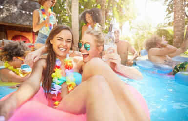 Porträt begeisterte, lachende junge Frauen Freunde trinken und spielen im Sommer Schwimmbad - CAIF27211