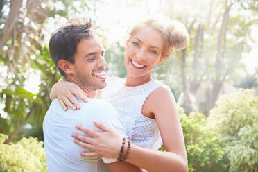 Portrait smiling young couple hugging in park - CAIF27217