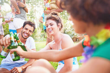 Junge Freunde, die im Sommer im Park abhängen und auf Bierflaschen anstoßen - CAIF27224