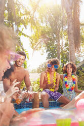 Young friends hanging out, talking and drinking at sunny summer swimming pool - CAIF27237