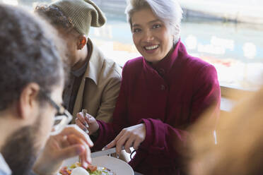 Portrait lächelnde junge Frau beim Essen mit Freunden im Restaurant - CAIF27254