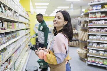 Lächelnde Lebensmittelhändlerin mit digitalem Tablet im Supermarkt - CAIF27300