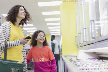 Glückliche Mutter und Tochter beim Einkaufen von Tiefkühlkost im Supermarkt - CAIF27307