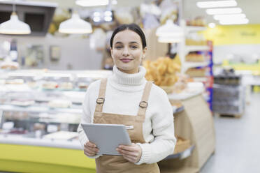 Porträt einer selbstbewussten Lebensmittelhändlerin mit digitalem Tablet im Supermarkt - CAIF27310