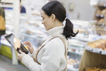 Lebensmittelhändlerin mit digitalem Tablet im Supermarkt - CAIF27314