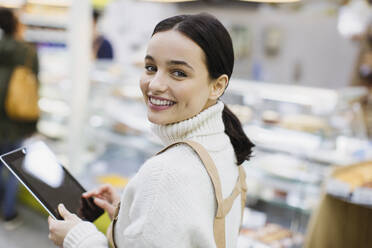 Porträt einer lächelnden, selbstbewussten Lebensmittelhändlerin mit digitalem Tablet im Supermarkt - CAIF27320