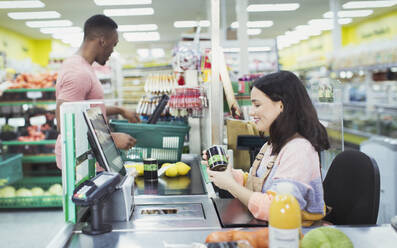 Cashier helping customer at supermarket checkout - CAIF27336
