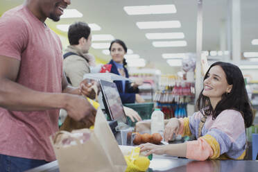 Freundliche Kassiererin hilft Kunden an der Supermarktkasse - CAIF27344