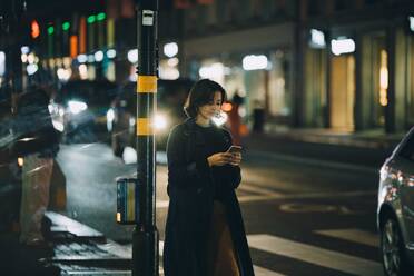 Frau, die nachts in der Stadt auf ihrem Handy surft - MASF17963