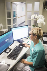 High angle view of mature female doctor working over computer while sitting in clinic - MASF18037