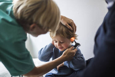 Ärztin untersucht das Ohr eines Jungen mit einem Otoskop im Krankenhaus - MASF18059