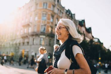 Smiling wrinkled woman looking away in city - MASF18194