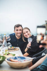 Glückliche Freunde mit Getränken posieren für ein Foto während einer Dachterrassenparty - MASF18234