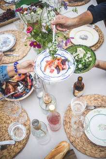 High angle view of cropped hand serving food to woman during social gathering at building terrace - MASF18248