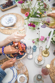 Hohe Winkel Ansicht der beschnittenen Hand gießen Wein, während Frau serviert Essen während geselliges Beisammensein auf der Terrasse - MASF18249