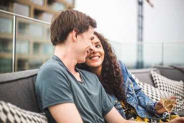 Lächelnder Mann mit Partnerin auf der Terrasse bei einem geselligen Beisammensein - MASF18254