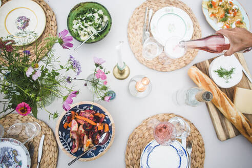 Hohe Winkel Ansicht der abgeschnittenen Hand gießen Getränk in Glas während Dinner Party - MASF18260