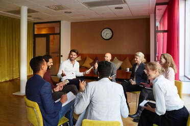 Lächelnde Unternehmer, die während eines Büro-Workshops im Kreis sitzend diskutieren - MASF18292