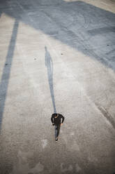 Hoher Blickwinkel eines Mannes, der ein Smartphone benutzt, während er auf einem Fußweg geht - MASF18371