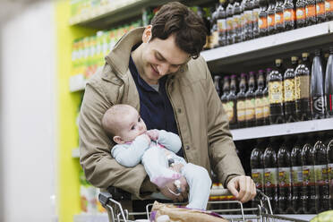 Vater mit kleiner Tochter beim Einkaufen im Supermarkt - CAIF27360