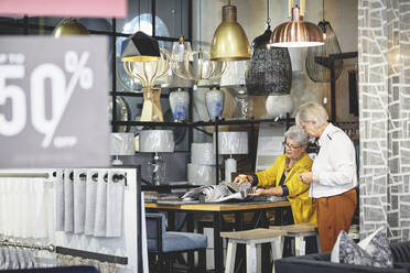 Ältere Frauen beim Einkaufen und Betrachten von Stoffmustern in einem Geschäft für Wohnkultur - CAIF27393
