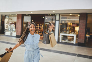 Portrait excited woman shopping in mall - CAIF27409