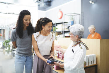 Frauen zahlen an der Kasse eines Einrichtungsgeschäfts - CAIF27417